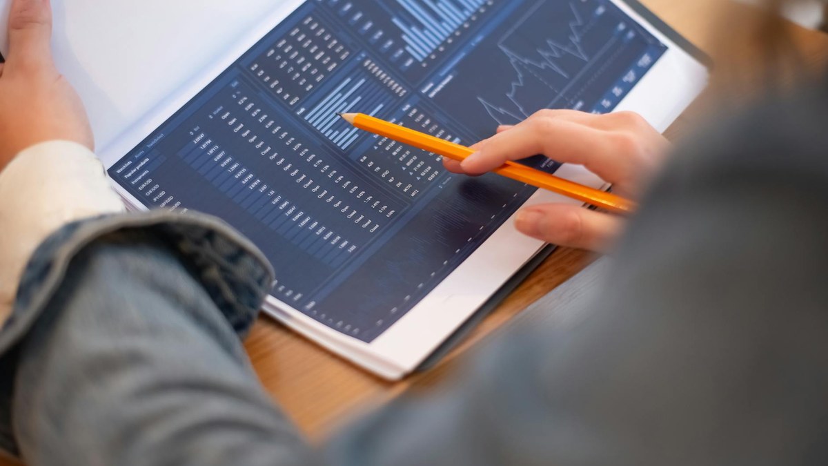 woman reviewing financial documents and graphs on a tablet, focused and analytical