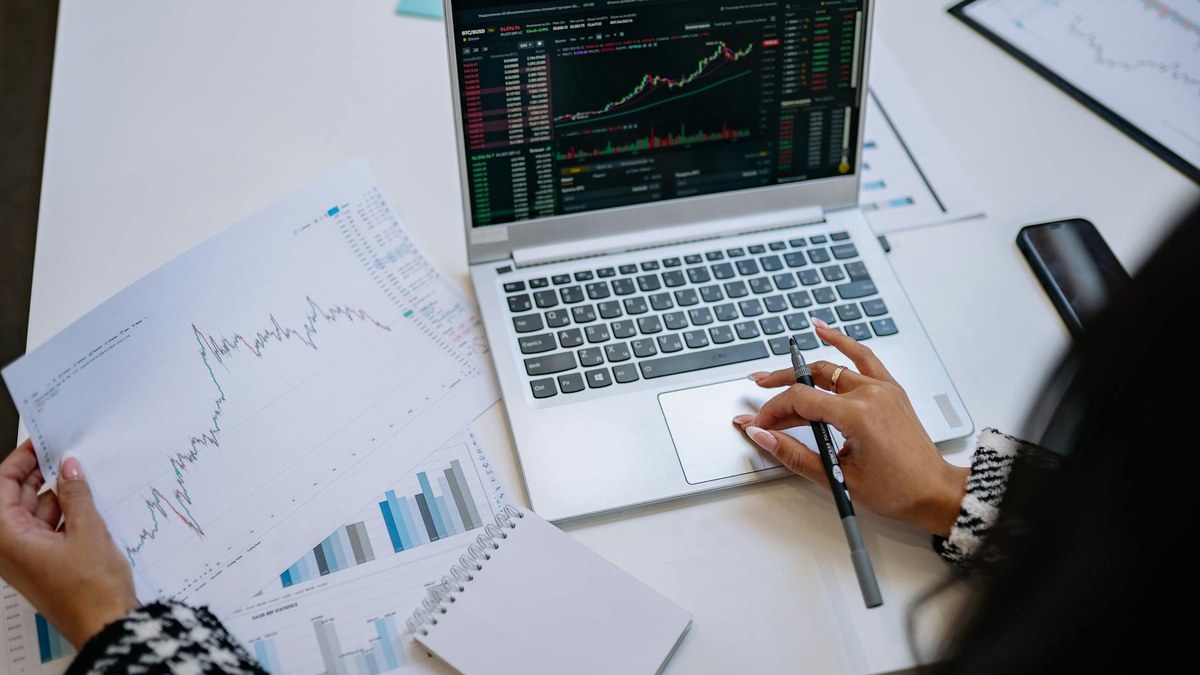 korean young woman thoughtfully looking at a notebook with financial charts