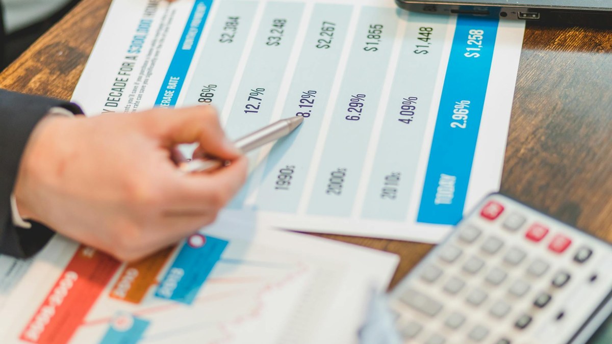 hand using calculator to sum up numbers on a financial report