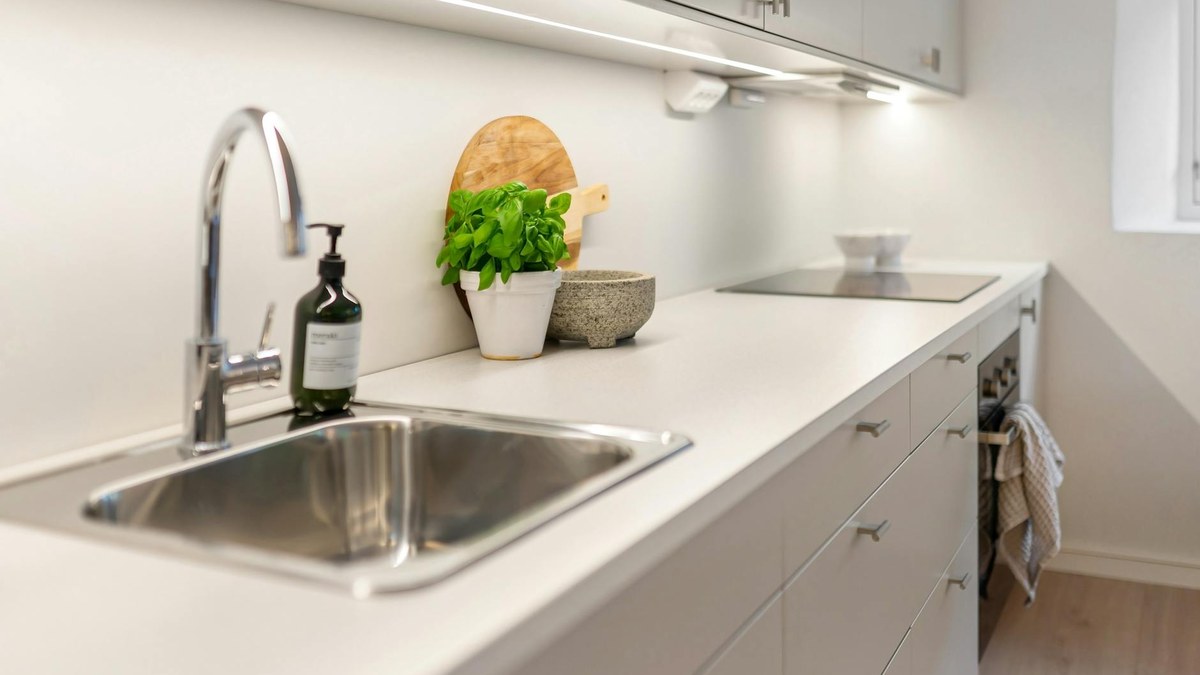 Stainless steel kitchen counter with clean utensils, cutting boards, and fresh vegetables