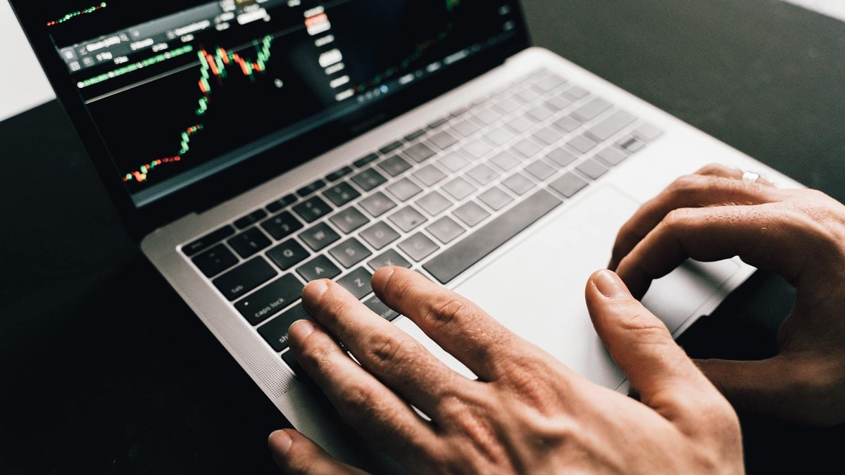 close-up of a hand typing on a keyboard with customer profile data on screen