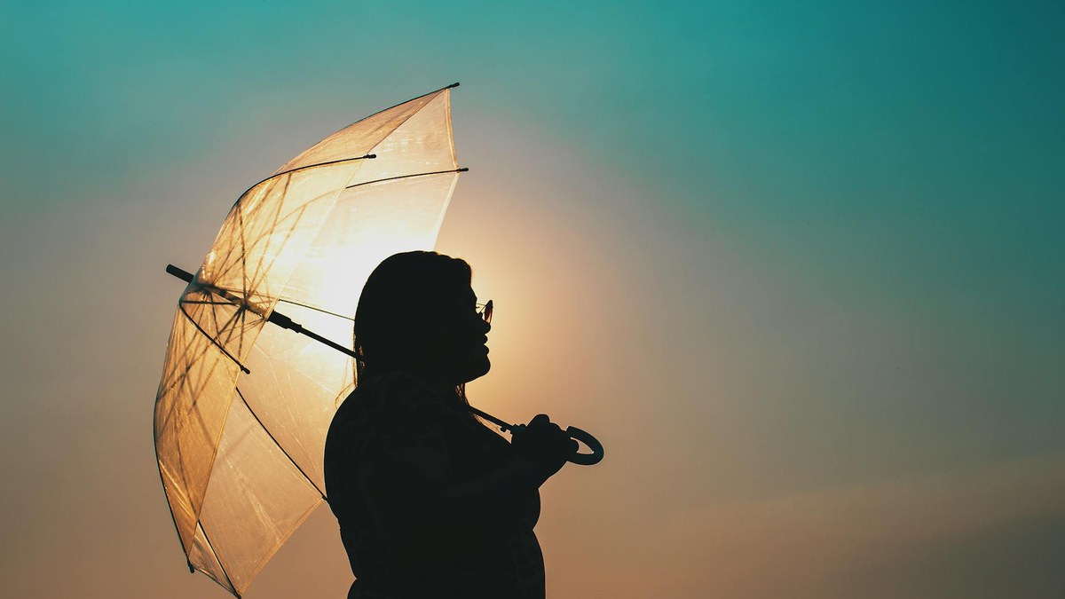 woman holding a compact automatic folding umbrella on a sunny day