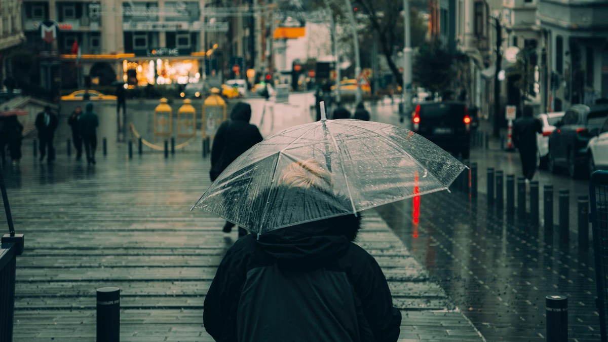 stylish person walking with a colorful umbrella in light rain