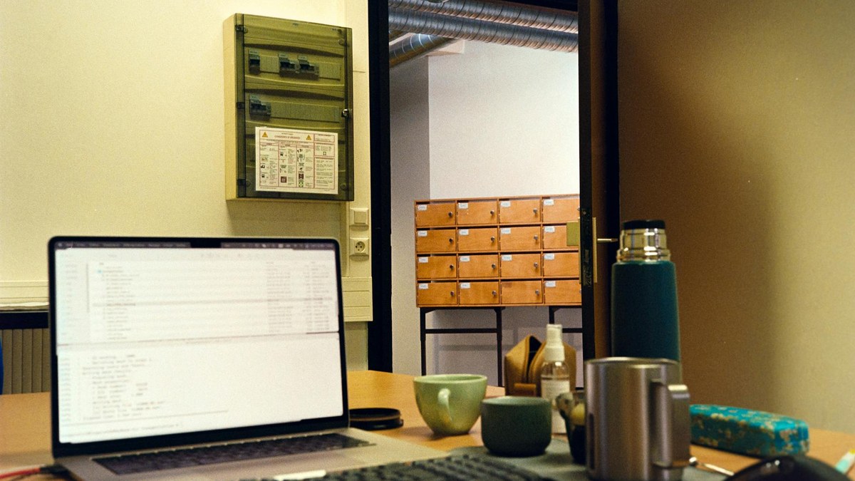 stainless steel thermos bottle placed on a clean office desk next to a laptop