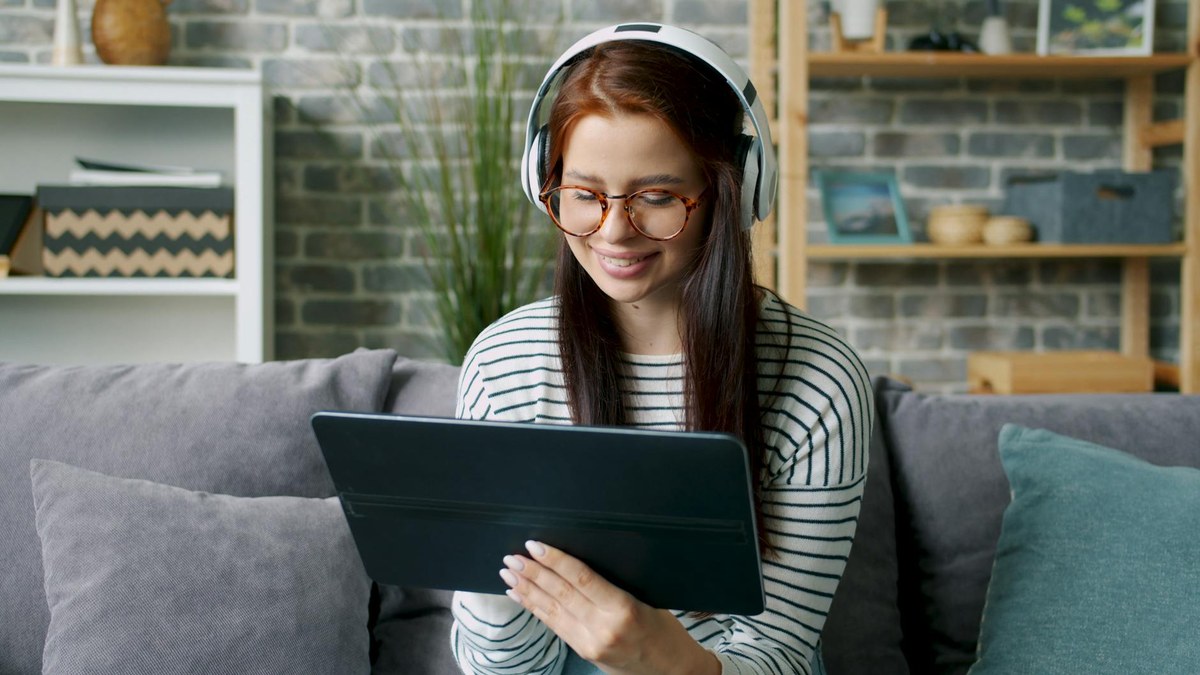 young korean office worker studying english with headphones and a tablet after work