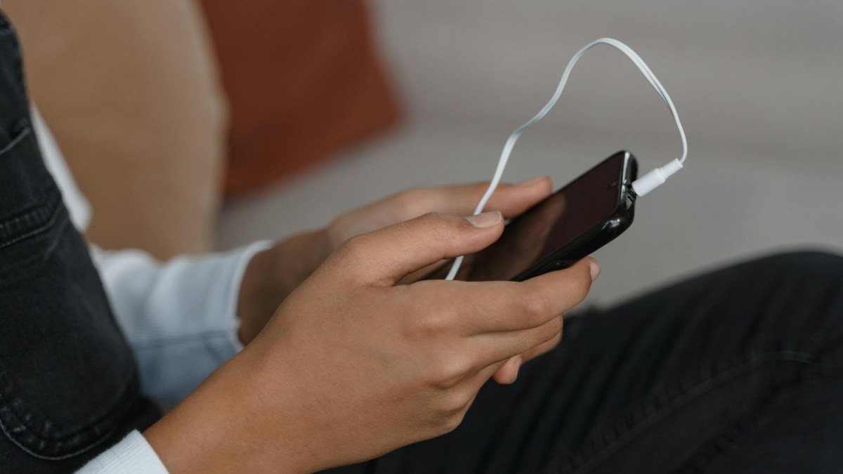 person shadowing english podcast with a smartphone and notebook