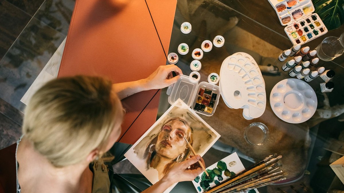 Young korean woman smiling while painting watercolor landscape in a cozy art studio