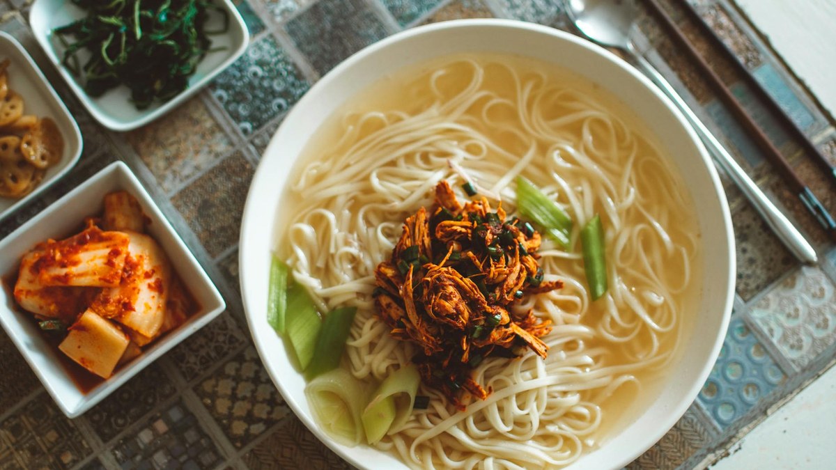 traditional korean noodles in a simple bowl on a wooden table
