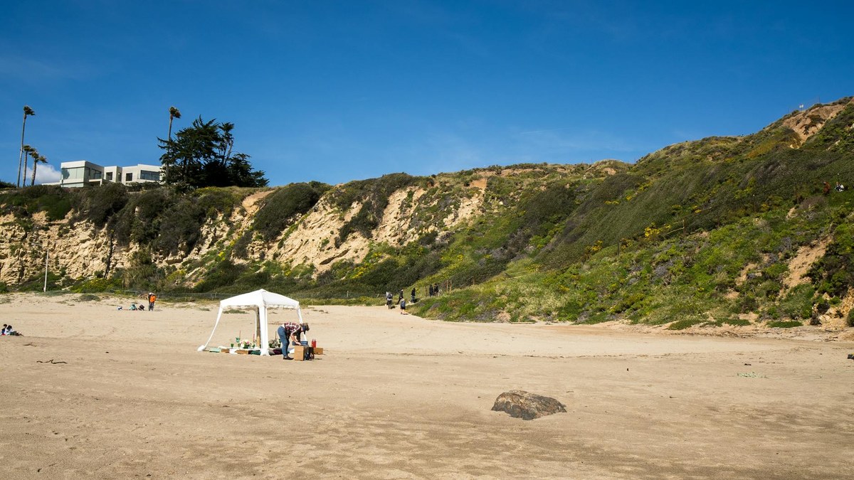 scenic view of a calm ocean beach with a few tents set up