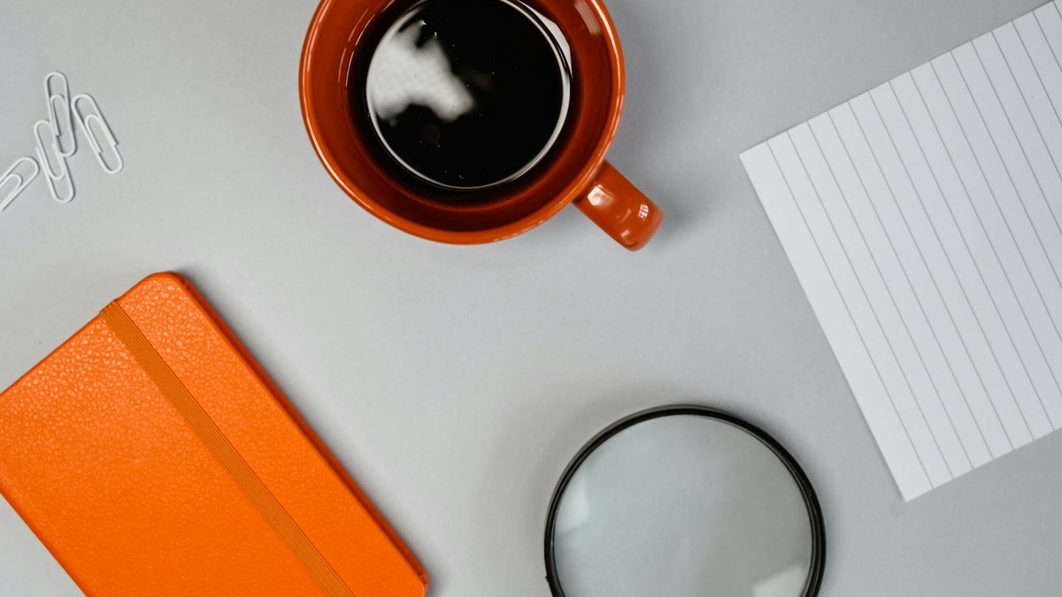 modern minimalist office desk with notebook and coffee, natural light