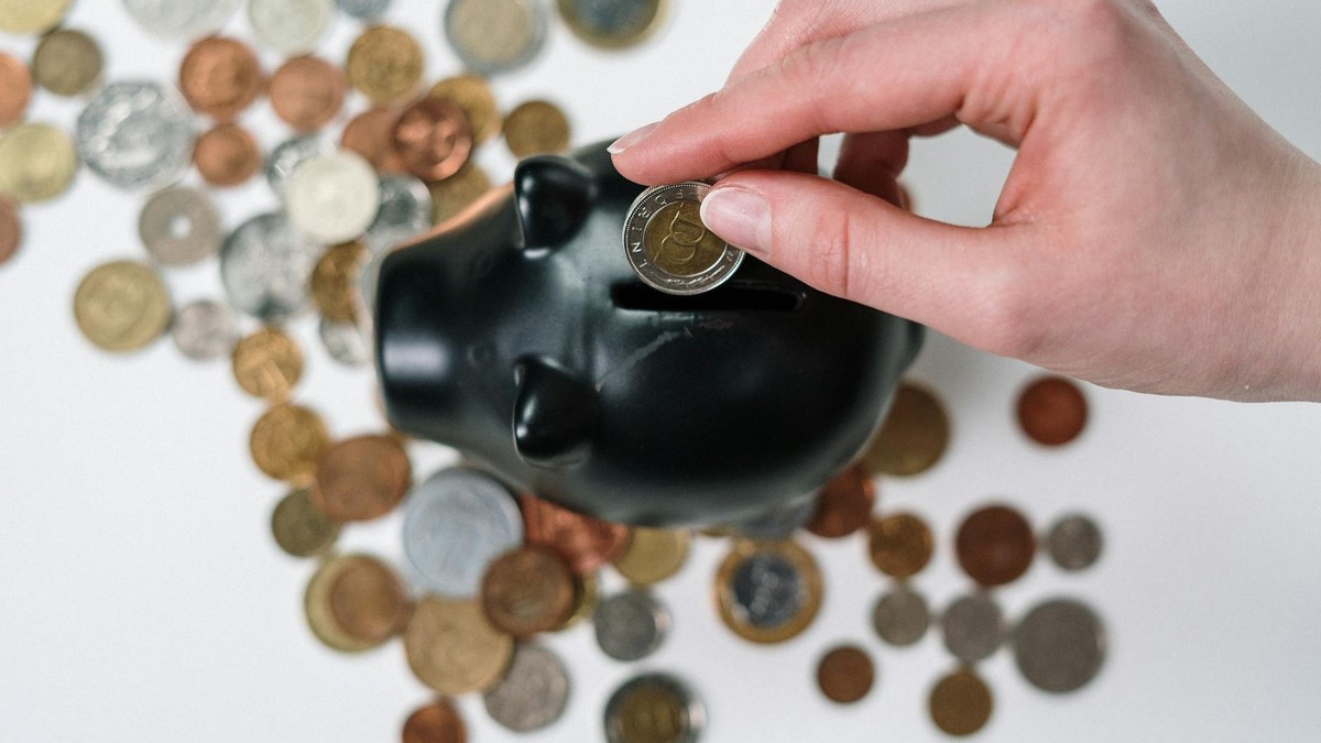 hand placing coin into a piggy bank with growth chart in background