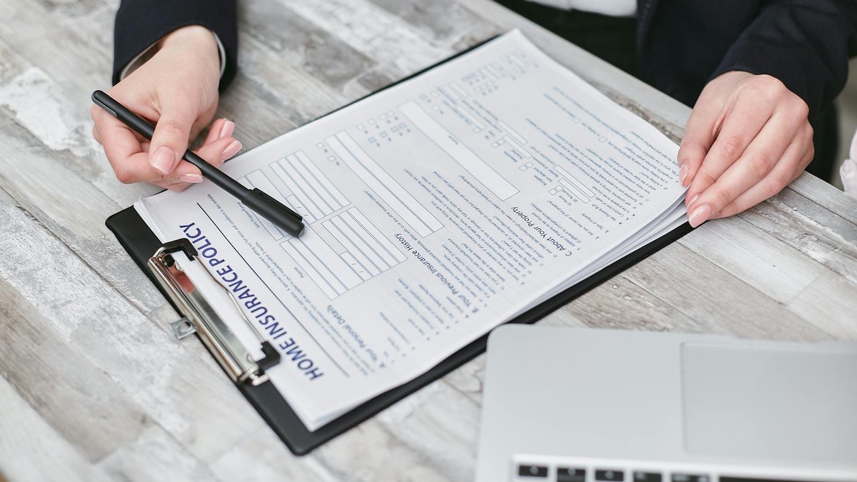 korean person comparing insurance documents on a laptop at home