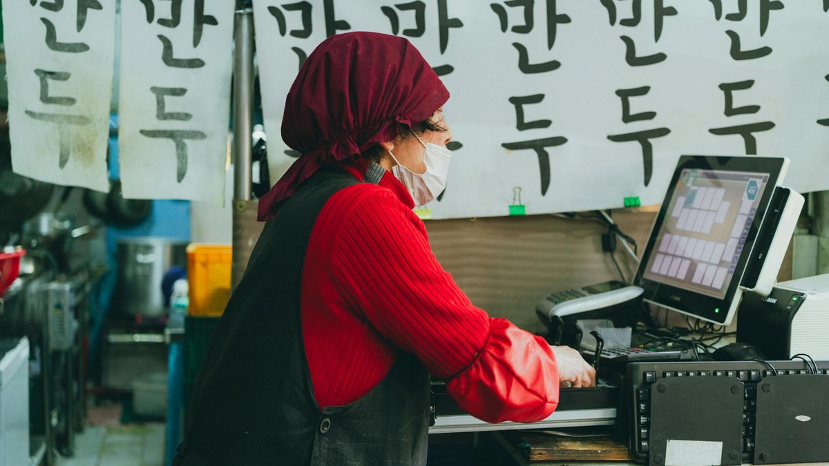 korean small business owner using laptop in a bright cafe
