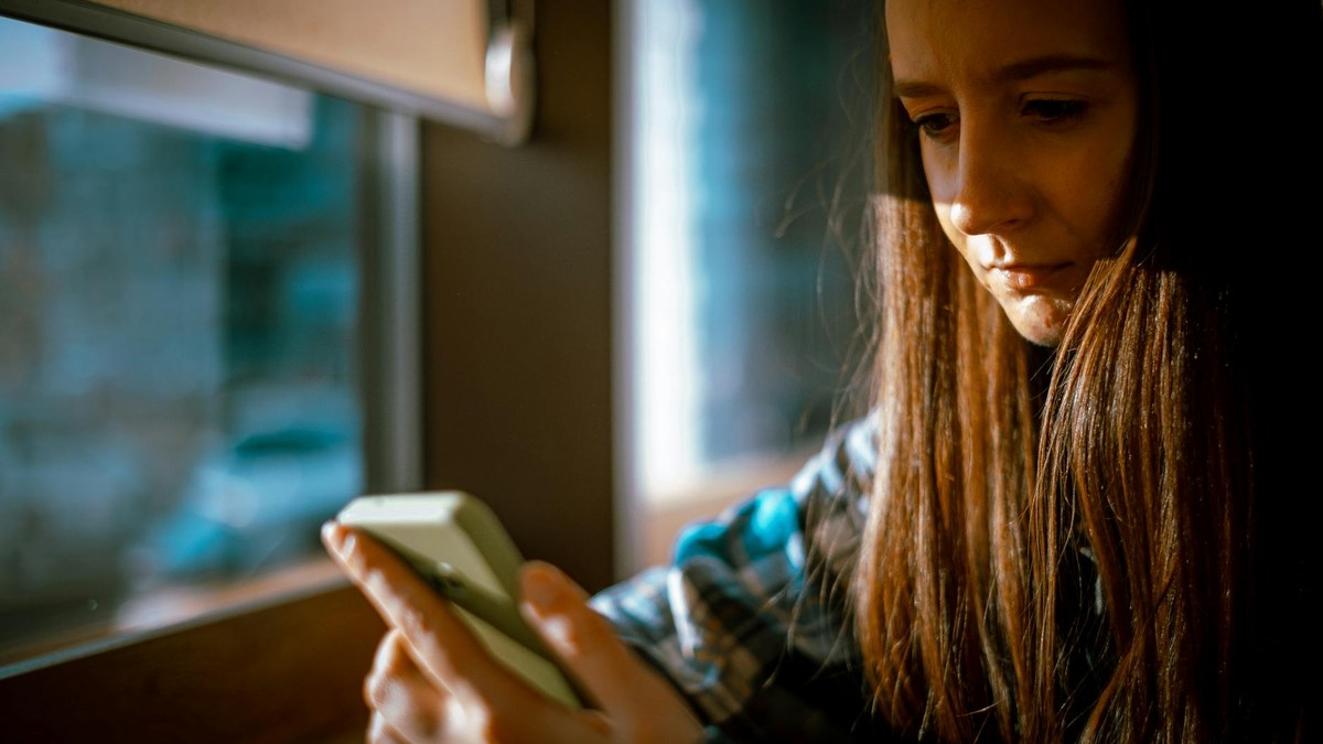 Person with poor posture looking down at smartphone, neck pain icon