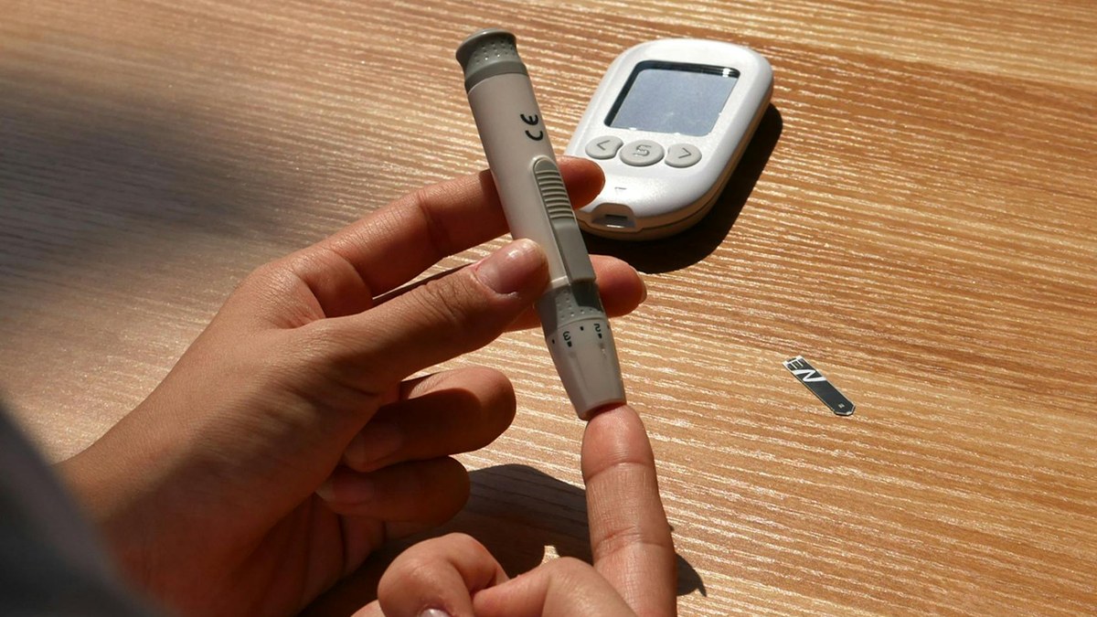 person measuring blood glucose level with a meter