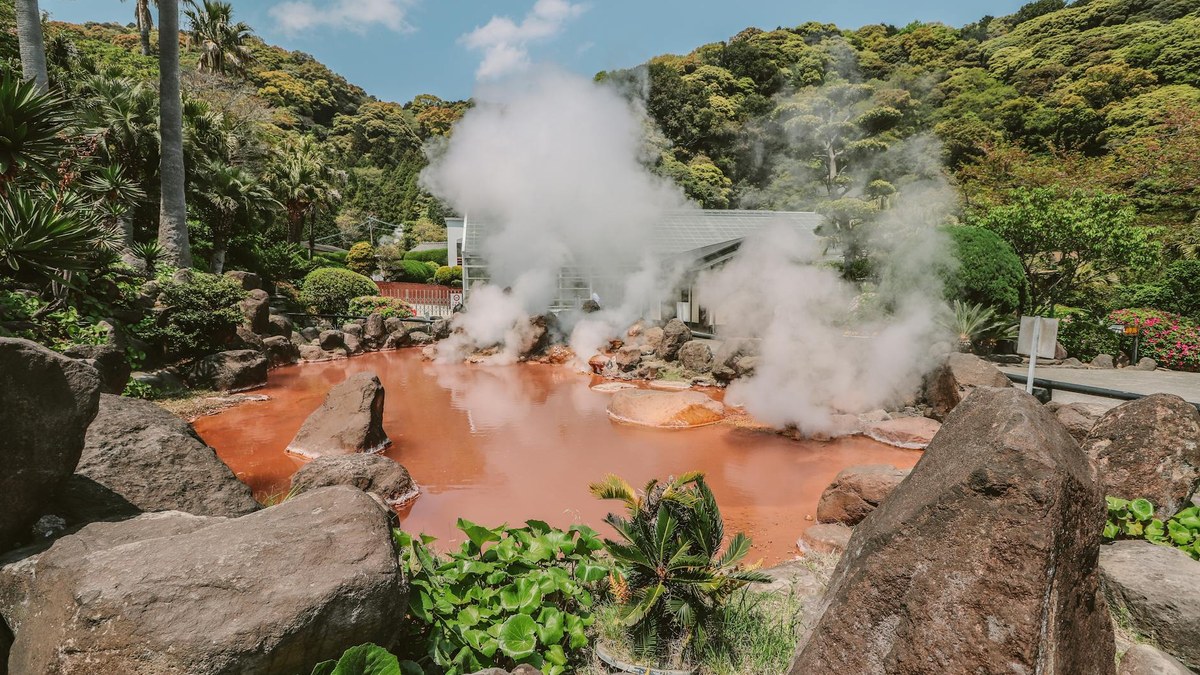 traditional Korean outdoor hot spring pool with steam rising, surrounded by trees
