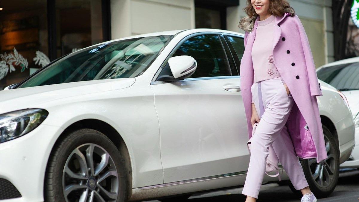 woman walking in a park wearing a light pastel jacket and white trousers